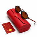 Cartier round sunglasses with matte black frame, brown lenses and red gold studded temples, displayed on red Cartier leather case with authenticity card