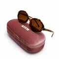 Miu Miu geometric octagonal sunglasses in tortoise shell with brown lenses, displayed on dusty rose velvet Miu Miu case