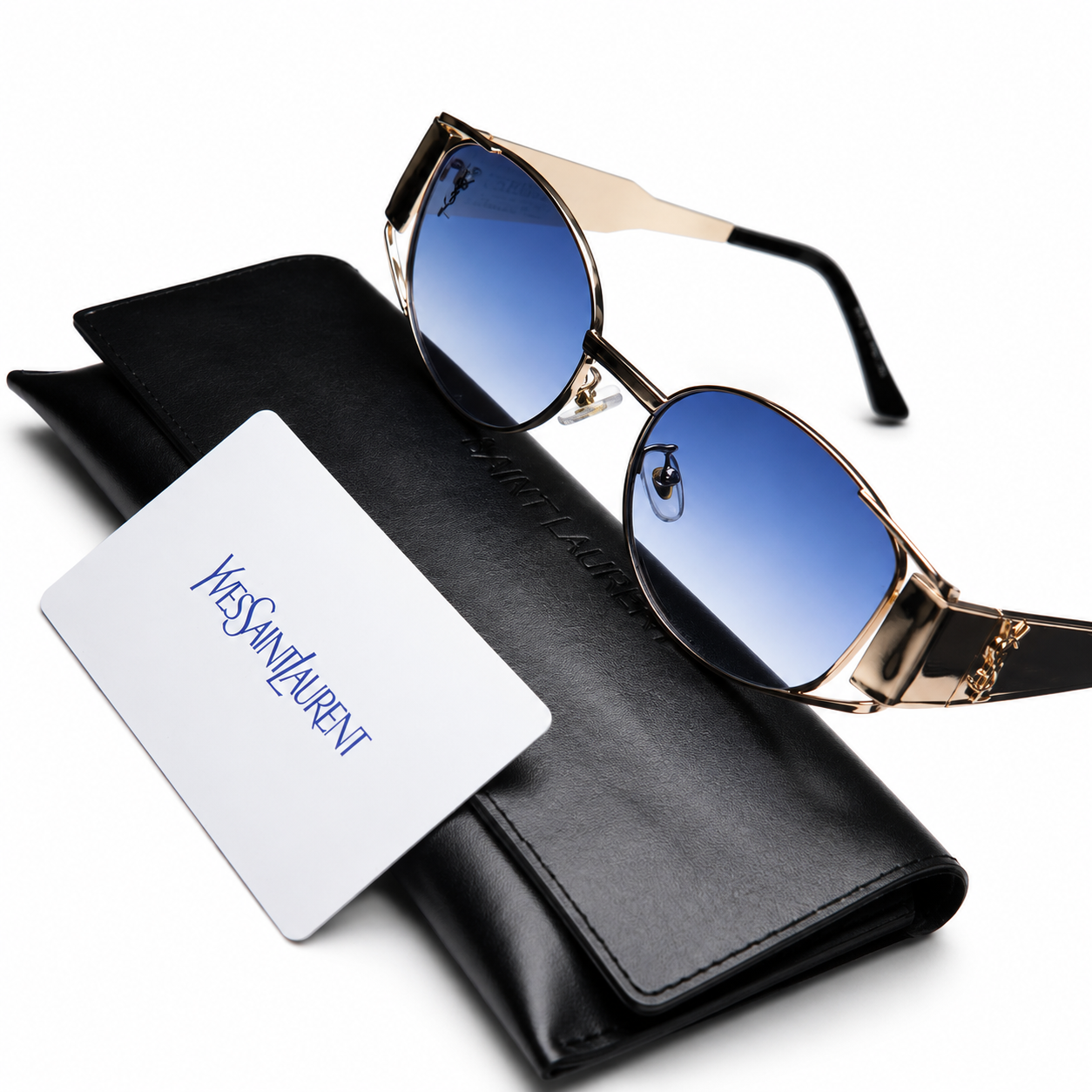 Yves Saint Laurent geometric sunglasses with gold metal frame and blue gradient lenses, displayed on black YSL leather case with authenticity card