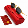 Cartier round sunglasses with 18k gold-tone frame, ornate fleur-de-lis hinge details and dark grey lenses, displayed on red Cartier leather case with authenticity card